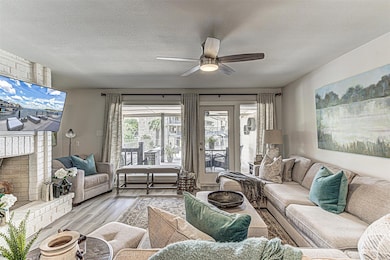 Living room featuring a fireplace, a textured ceiling, wood finished floors, and ceiling fan