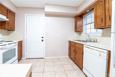 Kitchen with light tile flooring, white appliances, and stainless steel sink