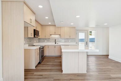 Kitchen with light brown cabinets, decorative backsplash, recessed lighting, modern cabinets, and appliances with stainless steel finishes