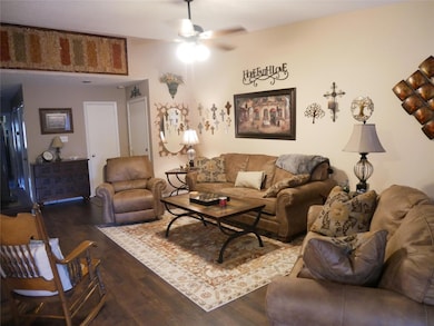 Living room featuring a ceiling fan and wood fini