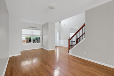 Unfurnished living room featuring stairs, light wood-style flooring, and arched walkways