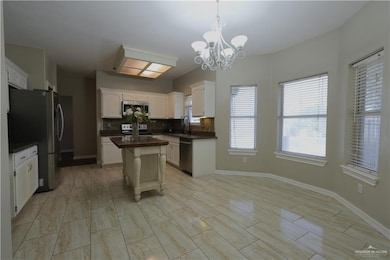 Kitchen with dark countertops, decorative backsplash, pendant lighting, stainless steel appliances, and a chandelier