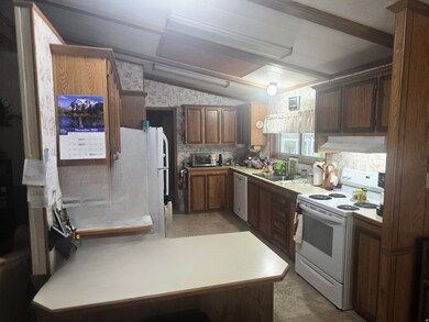 Kitchen with white appliances, light countertops, lofted ceiling, ventilation hood, and a peninsula