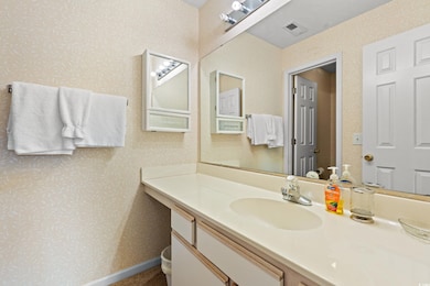 Bathroom with wallpapered walls and vanity