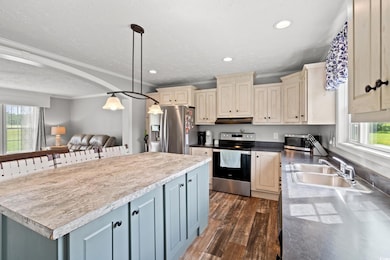 Kitchen with stainless steel appliances, crown molding, under cabinet range hood, plenty of natural light, and cream cabinetry
