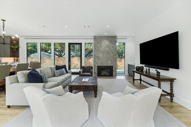 Elegant living space with beautiful fireplace and windows framing views of the landscaped side yard, complemented by a new brick boundary.