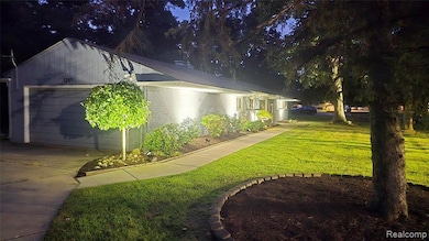 Property exterior at night featuring a garage, a lawn, concrete driveway, and brick siding