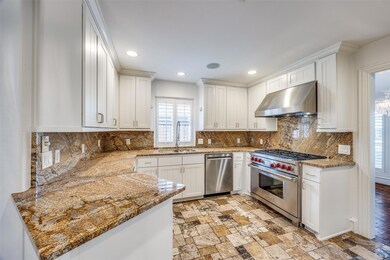 Kitchen featuring stainless steel appliances, stone countertops, white cabinets, and wall chimney range hood