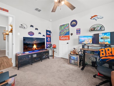 Carpeted home office featuring a ceiling fan and 
