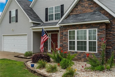 View of front of house with stone siding, an attached garage, a shingled roof, and concrete driveway