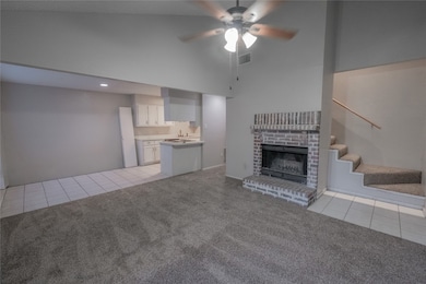Unfurnished living room with light tile patterned floors, light colored carpet, a fireplace, and high vaulted ceiling