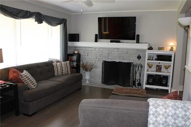 Den with brick fireplace and refinished wood floor