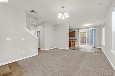 Unfurnished living room with light carpet, a chandelier, and light tile patterned floors