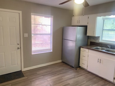 Kitchen with white cabinets, freestanding refrigerator, light wood-style flooring, and ceiling fan