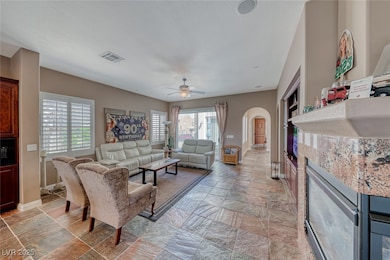 Living area with ceiling fan, arched walkways, vis