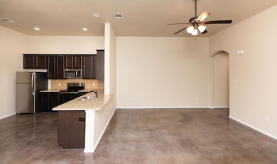 Kitchen with backsplash, stainless steel appliances, finished concrete flooring, dark brown cabinets, and light stone counters