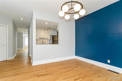 Unfurnished dining area featuring light wood-style flooring, track lighting, a chandelier, and recessed lighting
