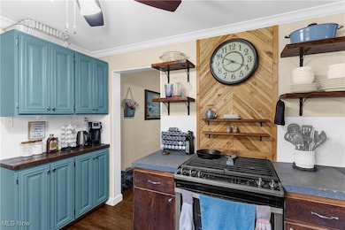 Kitchen with open shelves, decorative backsplash, blue cabinets, stainless steel gas range oven, and dark wood-style floors