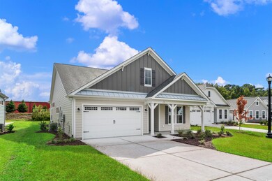 Craftsman inspired home featuring board and batten siding, a front lawn, driveway, a porch, and roof with shingles