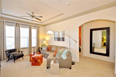 Living room featuring crown molding, ceiling fan, a raised ceiling, and carpet flooring