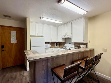 Kitchen featuring a breakfast bar, white appliances and cabinetry