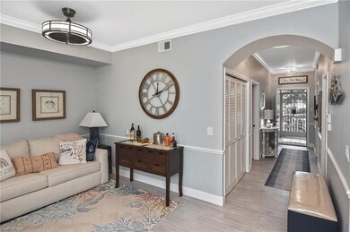 Living area featuring arched walkways, crown molding, and light wood finished floors