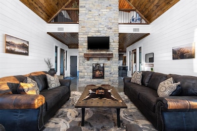 Living area with wooden walls, wood ceiling, high vaulted ceiling, and a fireplace