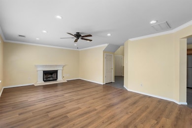 Unfurnished living room featuring crown molding, wood finished floors, recessed lighting, a ceiling fan, and a fireplace with raised hearth