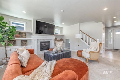 Living area with a tile fireplace, recessed lighting, and stairway