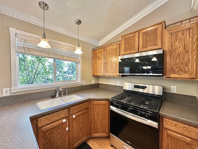 Kitchen view of GAS range/oven and microwave, lighting, sink, cabinets, window