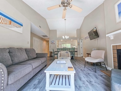 Living area with a chandelier, wood finished floors, high vaulted ceiling, a ceiling fan, and a tile fireplace