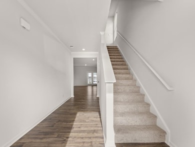 Robie front entryway into two story single family home with a carpet staircase to the right and hardwood like flooring