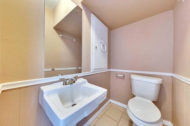 Bathroom with toilet, a wainscoted wall, tile pat