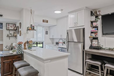 Kitchen with stainless steel appliances, a kitchen breakfast bar, light countertops, white cabinets