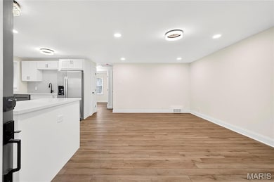 Kitchen with light countertops, white cabinets, recessed lighting, light wood finished floors, and stainless steel fridge with ice dispenser