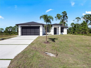 View of front facade with a front yard, concrete driveway, stucco siding, and a garage