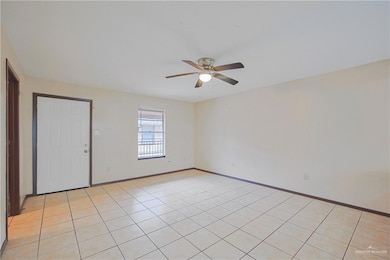 Empty room with a ceiling fan, baseboards, and light tile patterned floors