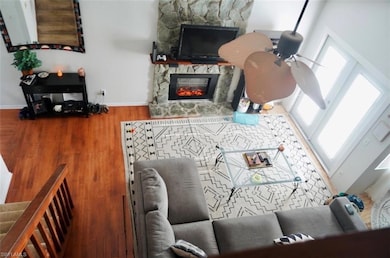 Living room with baseboards, a stone fireplace, wo