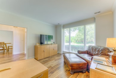 Living area with ornamental molding, light wood-style floors, and baseboards