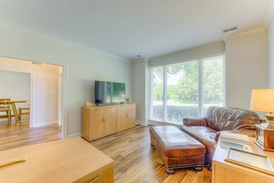 Living area with ornamental molding, light wood-style floors, and baseboards