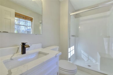 Bathroom with vanity, an enclosed shower, and toil