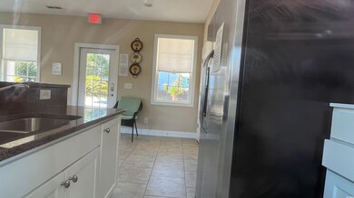 Club house Kitchen featuring stainless steel refrigerator with ice dispenser, white cabinets, dark stone counters, and light tile patterned flooring