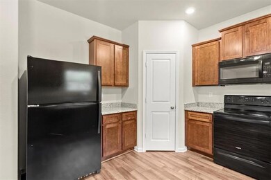 Kitchen with black appliances, light wood-style fl
