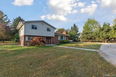 View of front facade featuring brick siding, a chimney, and a front lawn
