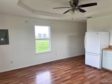 Kitchen with freestanding refrigerator, electric panel, wood finished floors, and a ceiling fan