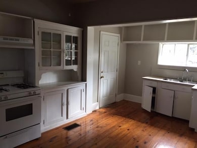 Kitchen featuring white gas range oven, light wood-style flooring, ventilation hood, light countertops, and white cabinets