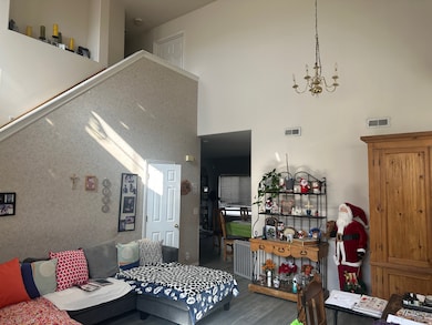 Living room featuring a high ceiling, wood finished floors, and a chandelier
