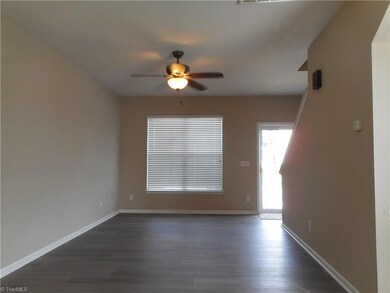 Living Room: Room features vinyl plank flooring for easy cleaning, two windows for natural lighting, and a ceiling fan with light. In this view we can see the front entry door and the stairs to the second floor are on the right side.