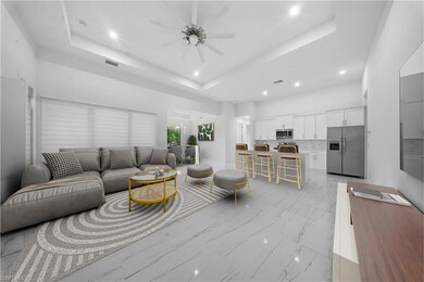 Living area featuring a raised ceiling, recessed lighting, light marble finish floors, and a ceiling fan