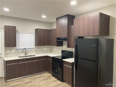 Kitchen featuring light hardwood / wood-style floors, black appliances, dark brown cabinetry, and sink